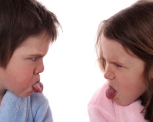 Two arguing children stick their tongues out at one another.