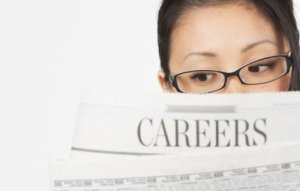 Professional woman reading career section of a newspaper.