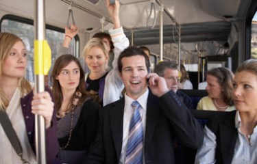 Man talks on his cell phone on a bus, while other passengers glare at him.